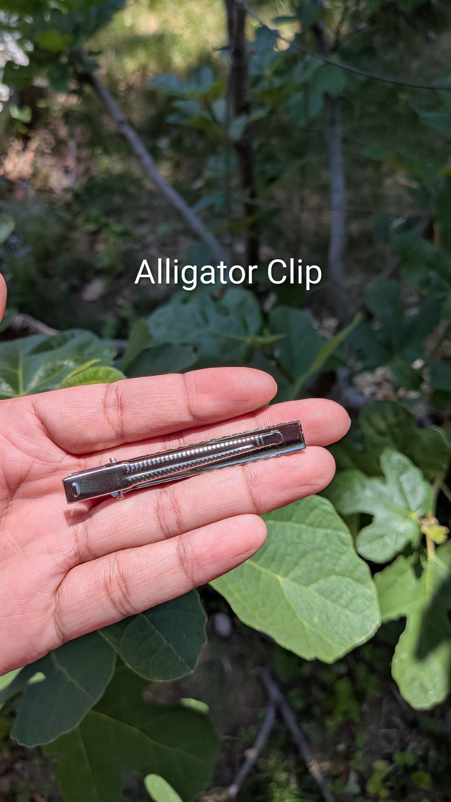 Alligator clip held in a hand with a natural background