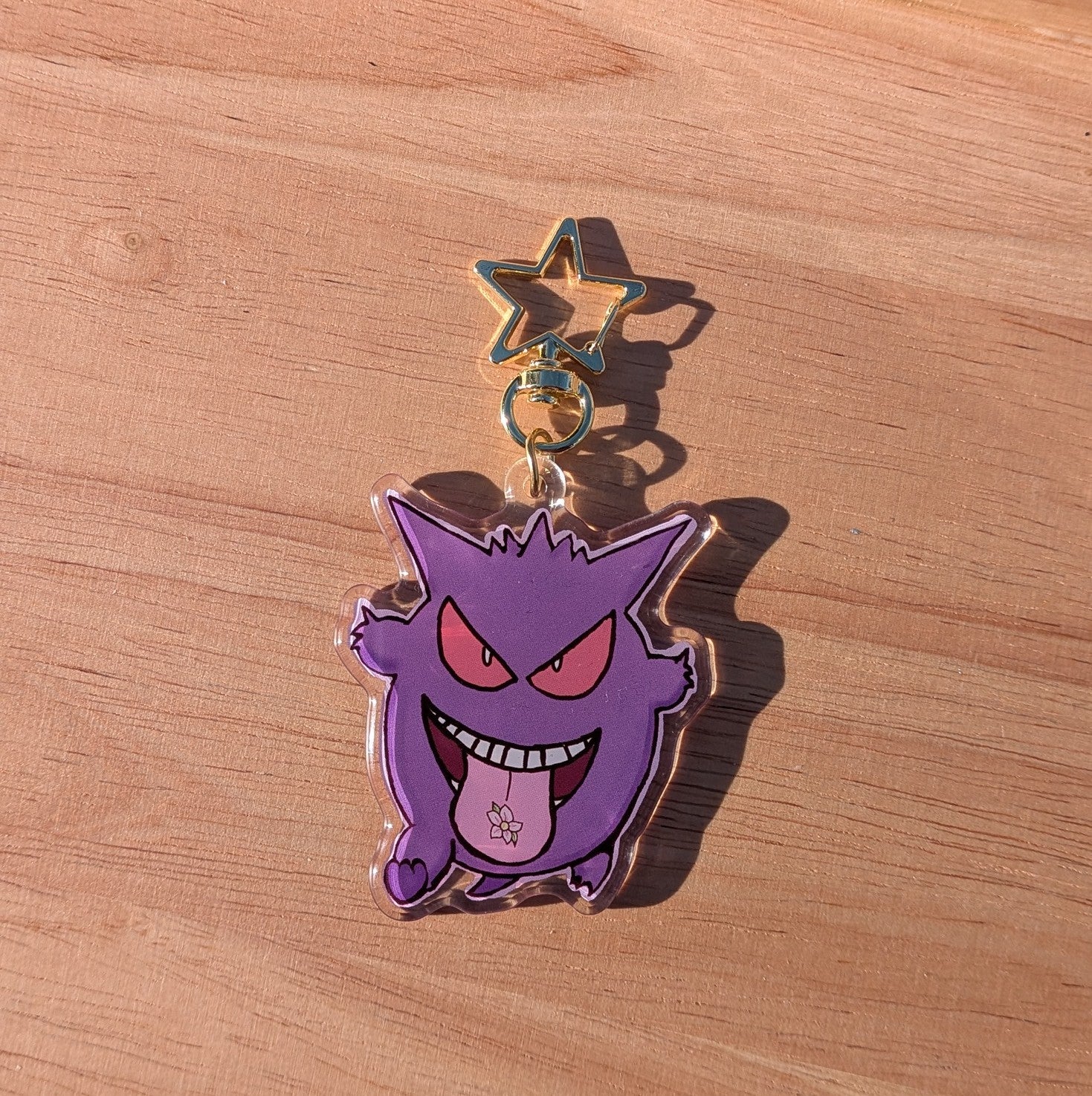 Purple cartoon character charm with a gold star on a wooden surface