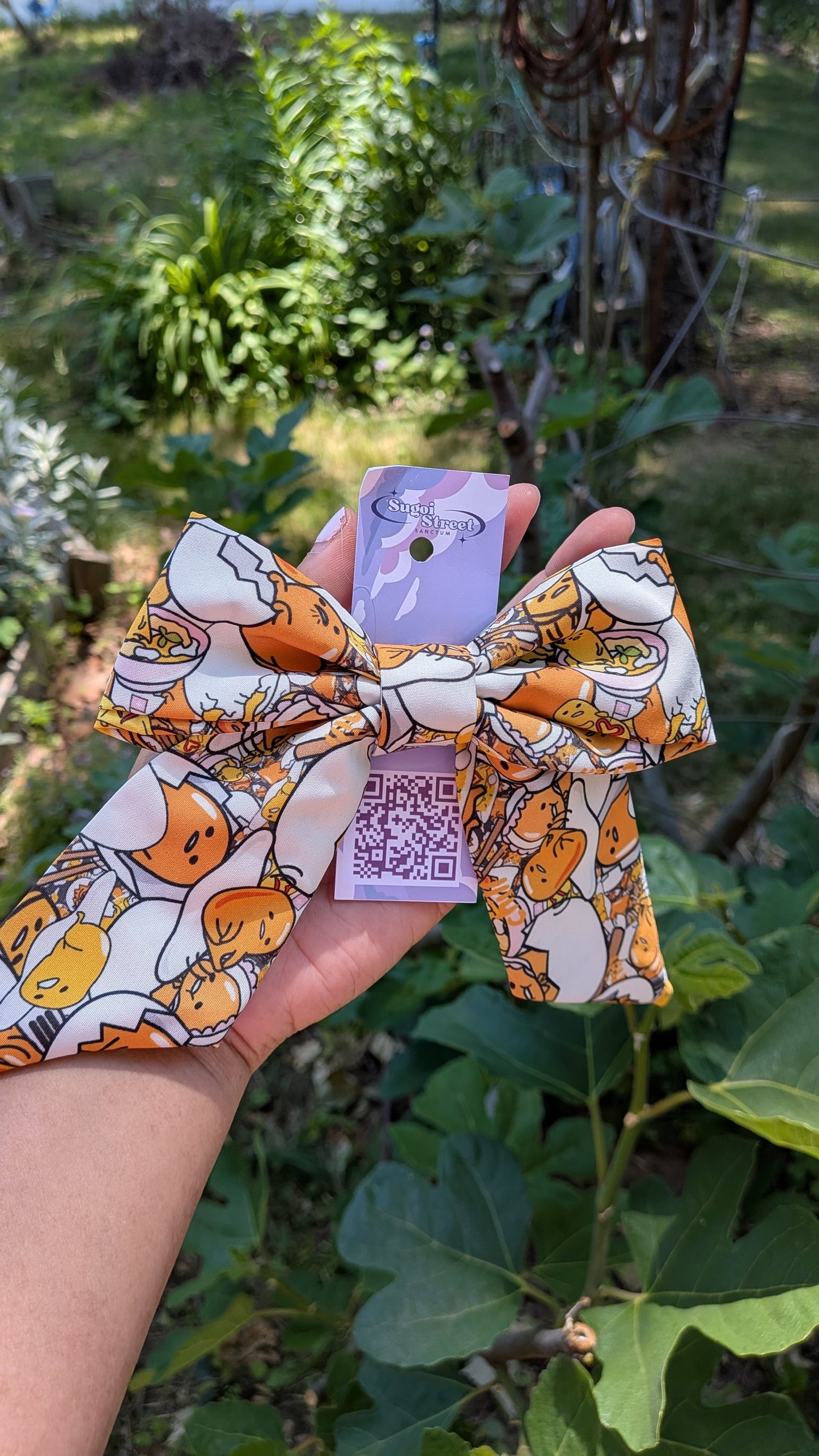 Hair bow with gudetama design held in front of a natural background
