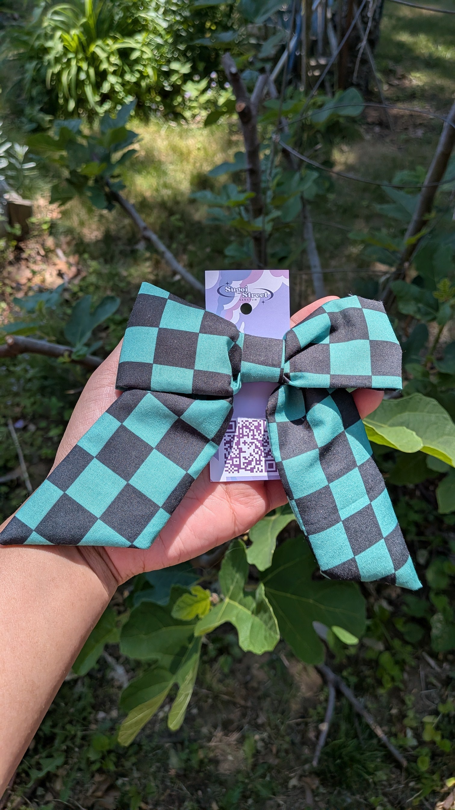 Checkered bow held by a hand with a blurred natural background