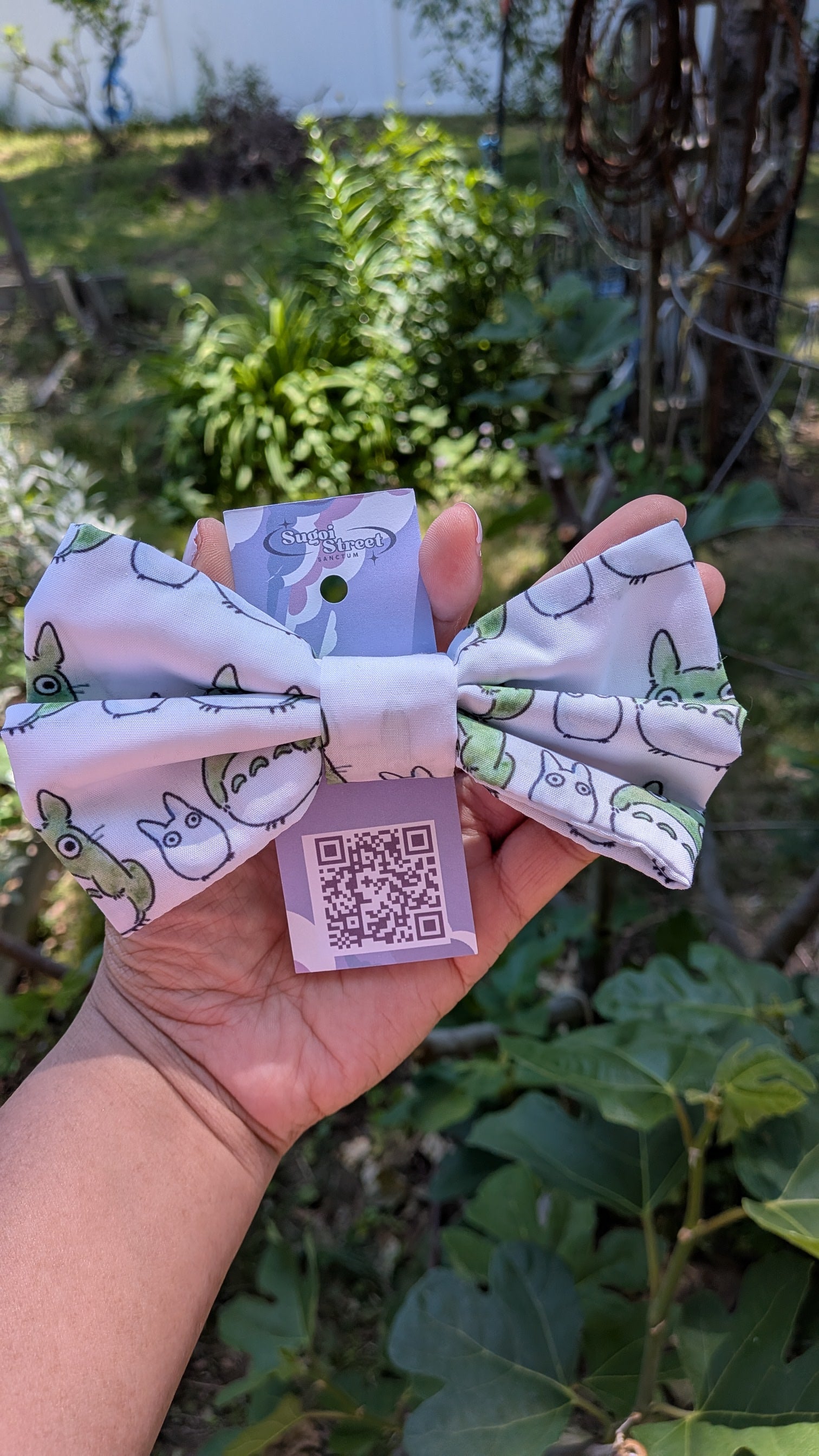 Hand holding a large fabric bow with totoro pattern
