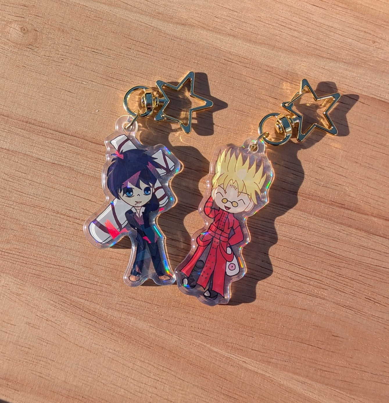 Two chibi anime-style keychains on a wooden surface