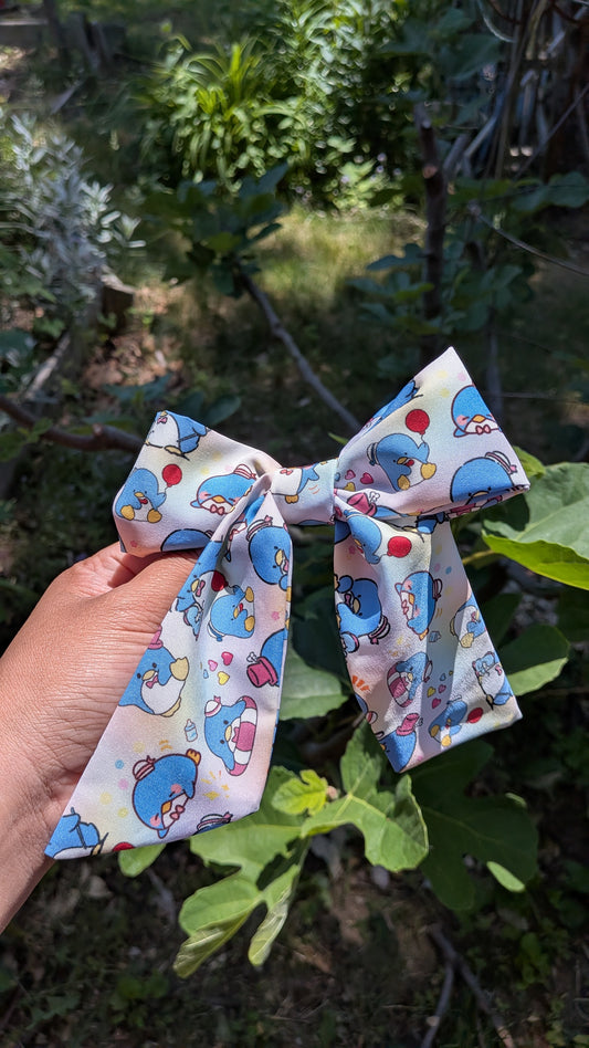colorful bow with tuxedo sam pattern held against a natural background with greenery.